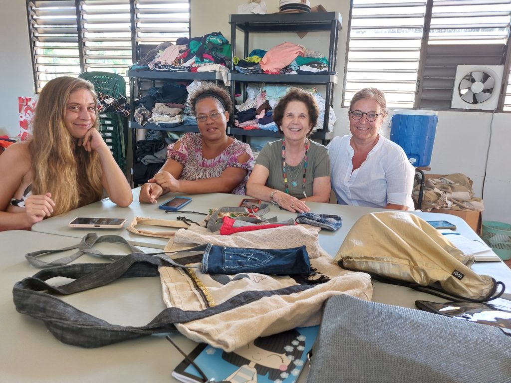 vier Frauen an einem Tisch auf dem selbstgemachte Taschen liegen