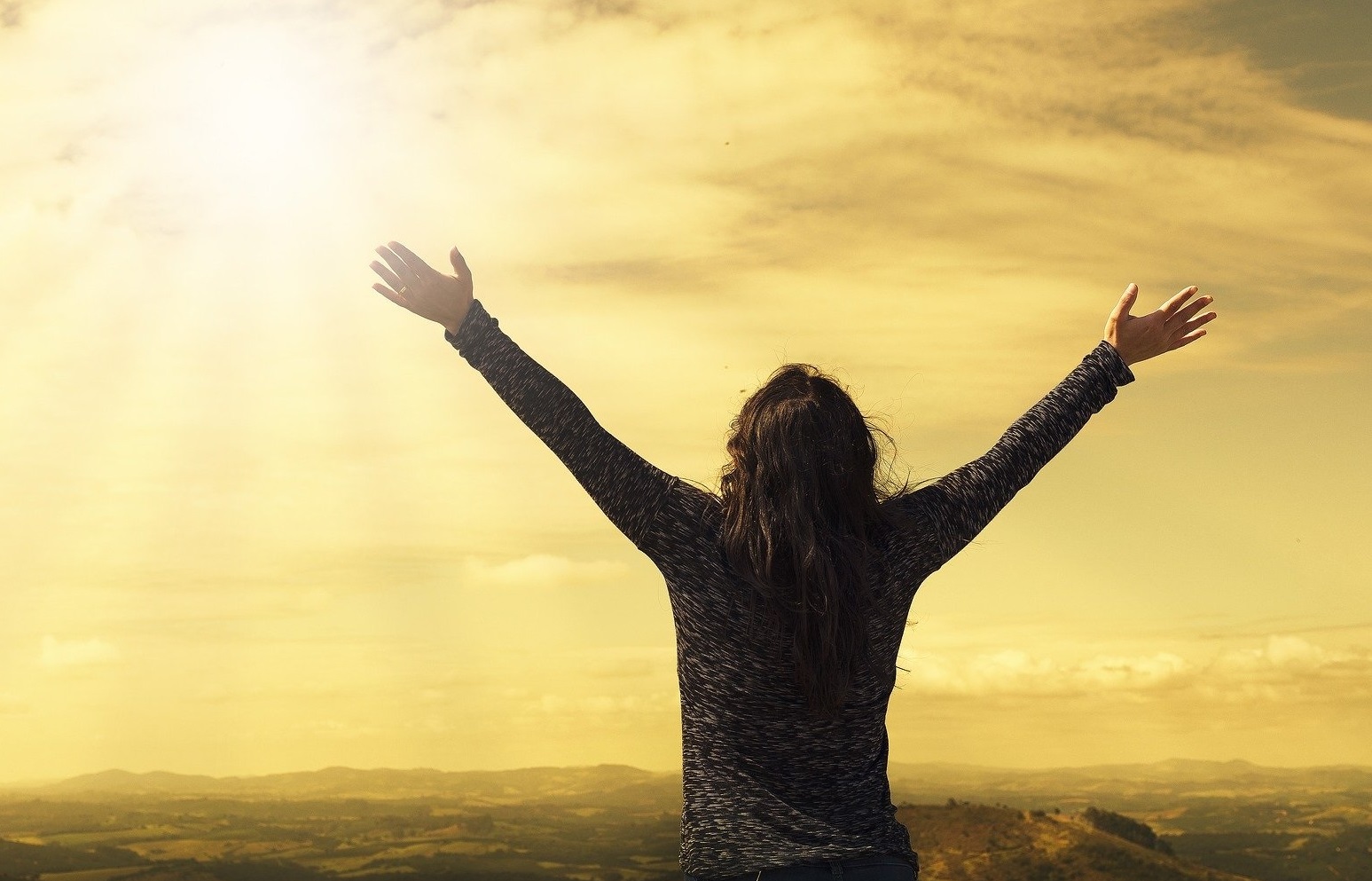 Frau schaut zur Sonne in die Ferne.