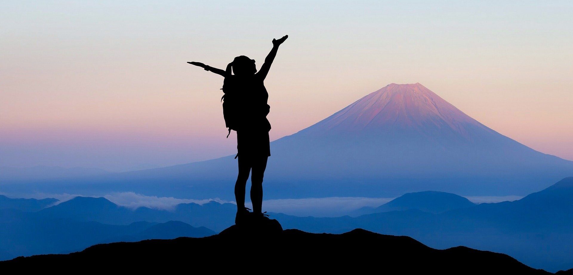 Eine Frau steht auf einem Berg und jubelt.
