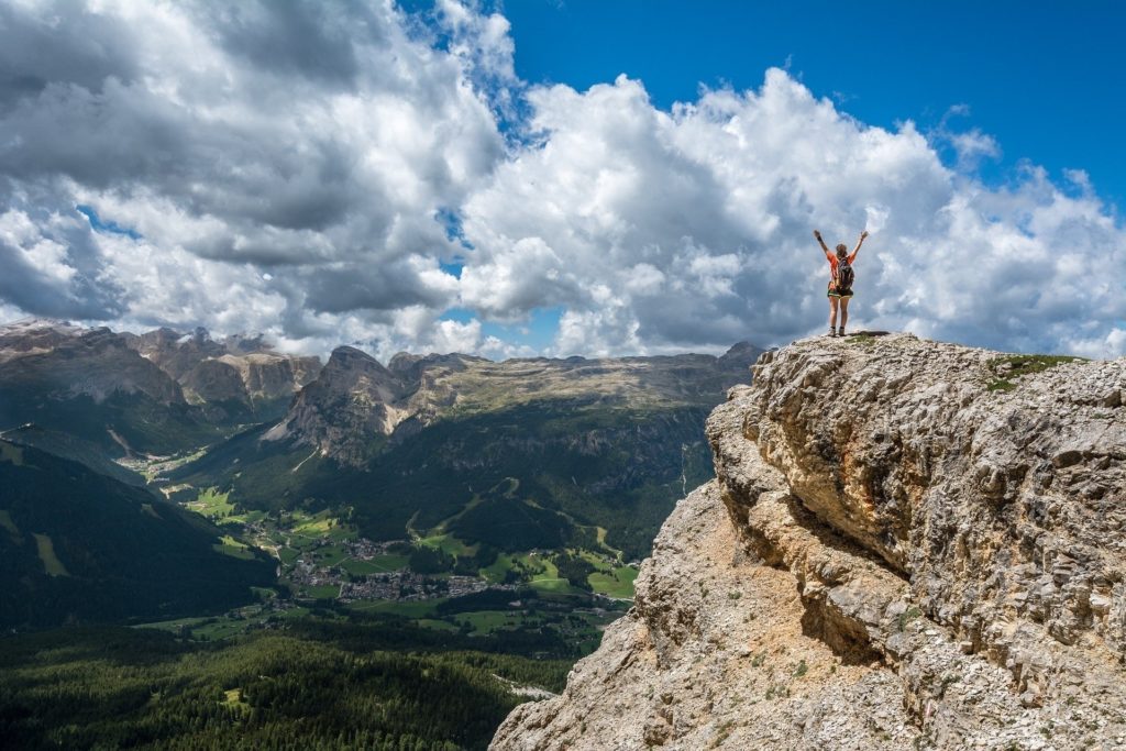 Wanderer auf einem Berg mit Bergen und Wolken im Hintergrund