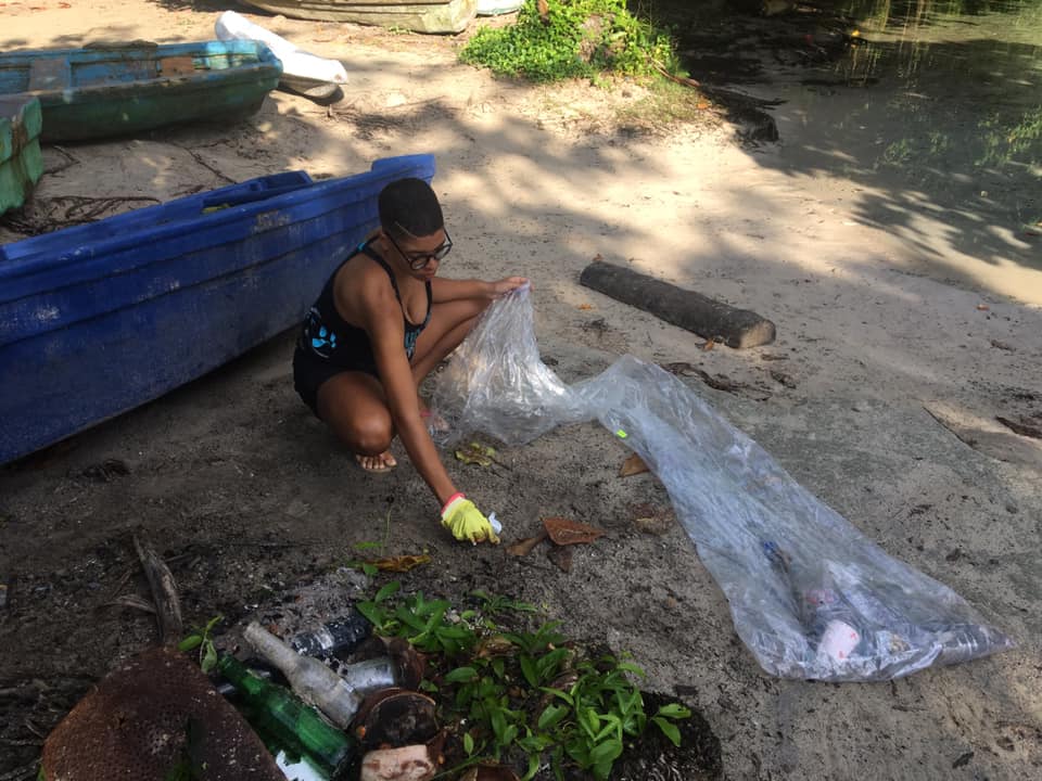 eine Frau beim Müll sammeln am Strand