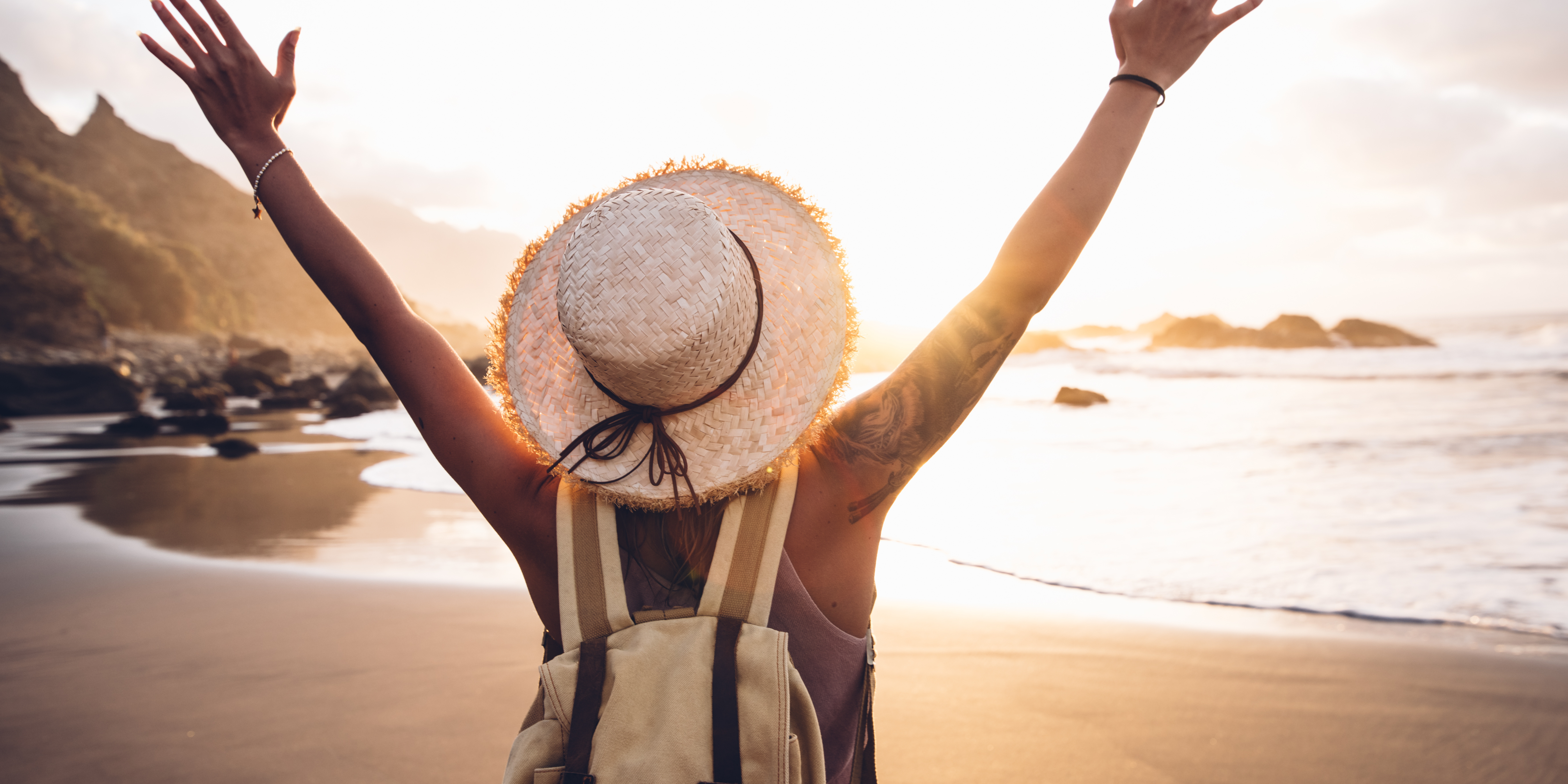 Frau am Strand die die Arme hochhebt
