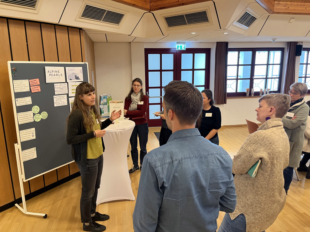 Participants standing in front of a bulletin board listening to a presentation.