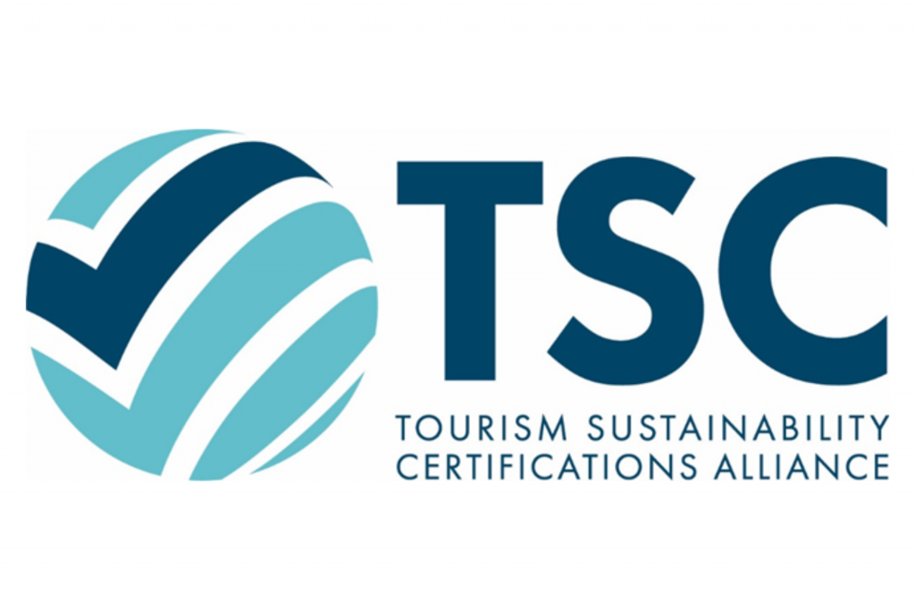 Tourism Sustainability Certifiactions Alliance © On the left, there is a round logo resembling a turquoise sphere with a dark blue checkmark. On the right, the letters "TSC" appear, with the description "Tourism Sustainability Certifications Alliance" written below in dark blue text.